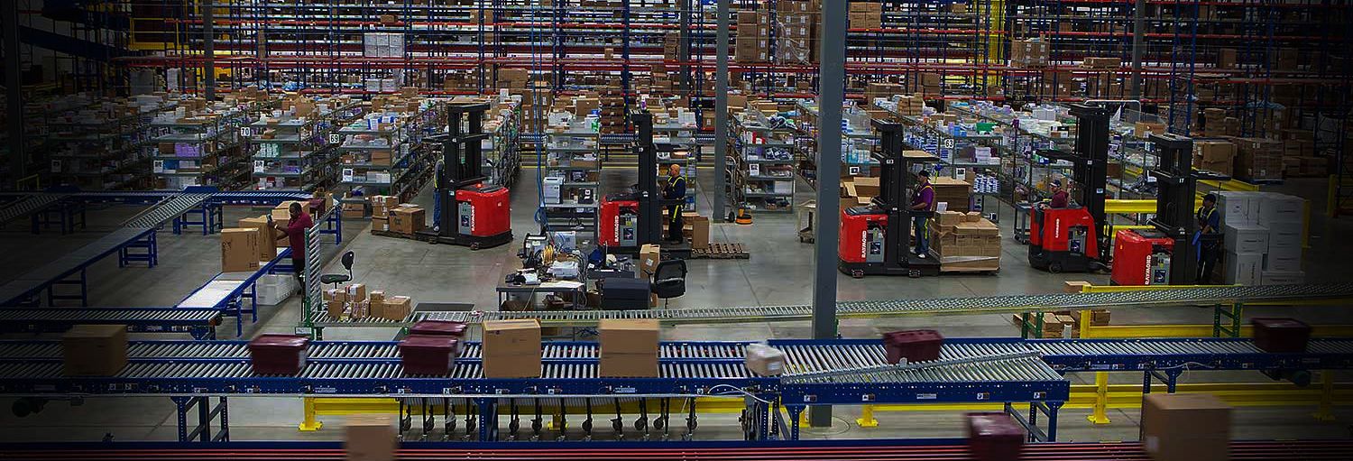 Warehouse with numerous red Raymond forklifts and conveyors moving material