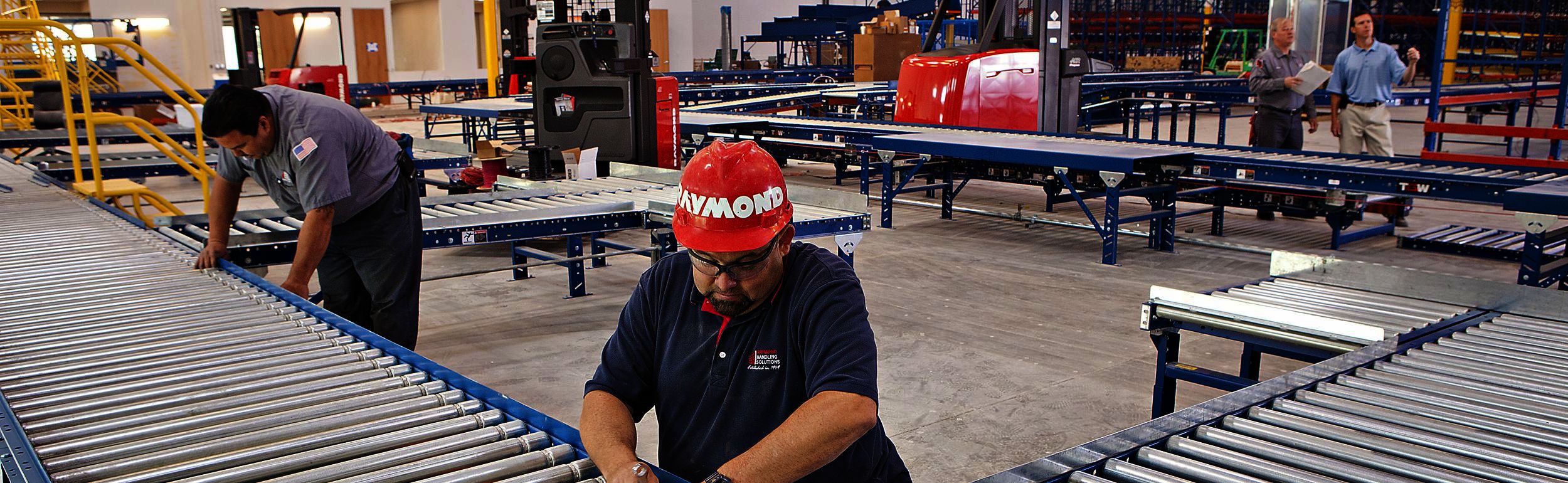 Man in red Raymond hard hat working on conveyor