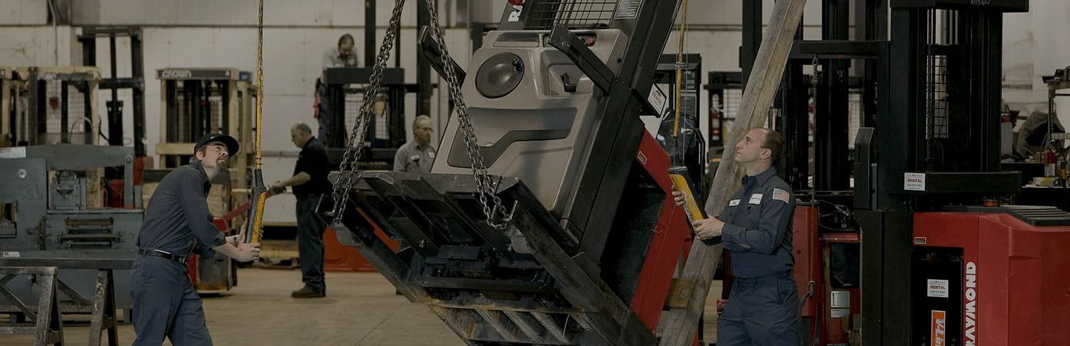 Forklift repair workers raising forklift with chain