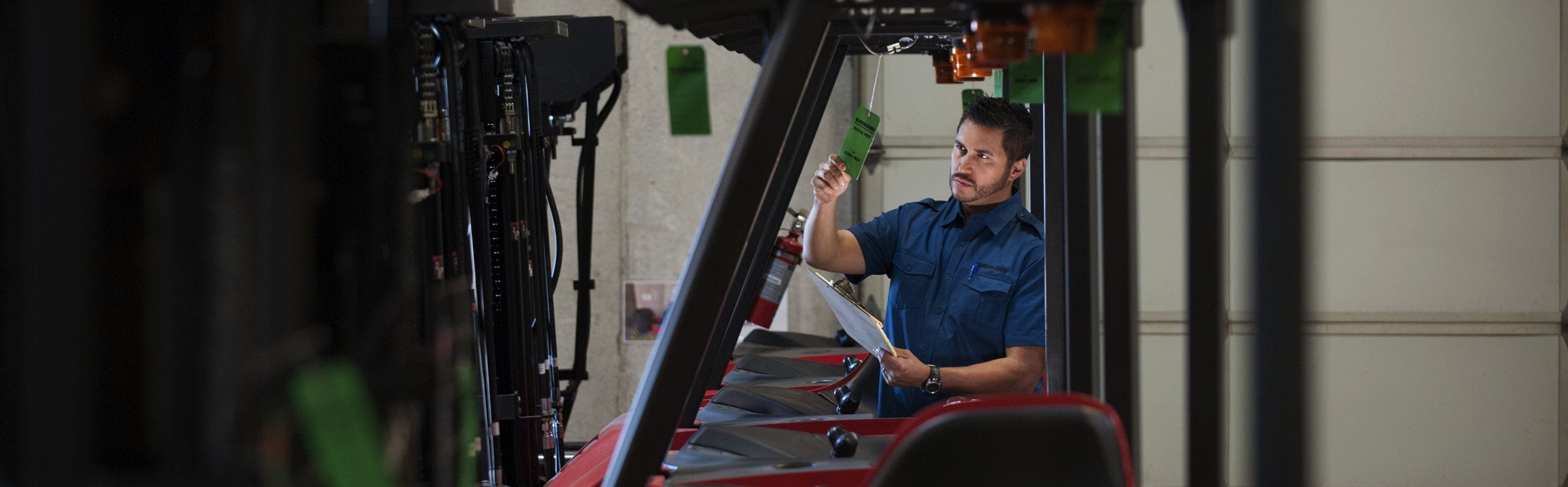 Man in blue shirt inspecting line of forklifts