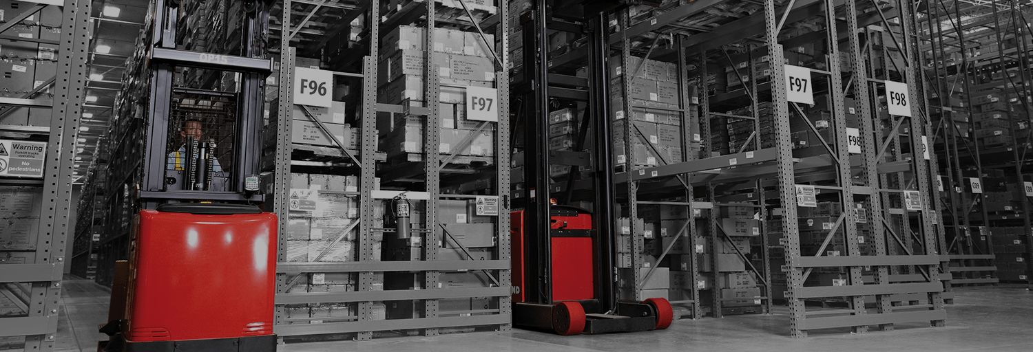 Man operating a Raymond swing reach truck (turret forklift) in a warehouse