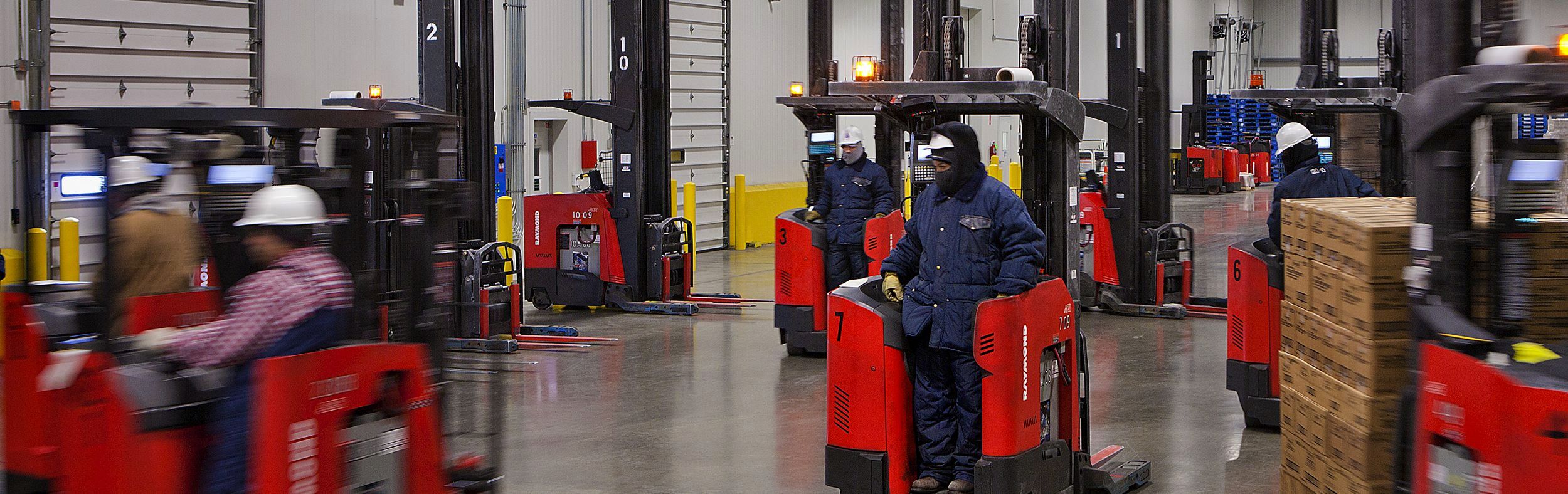 Various forklifts moving around warehouse.