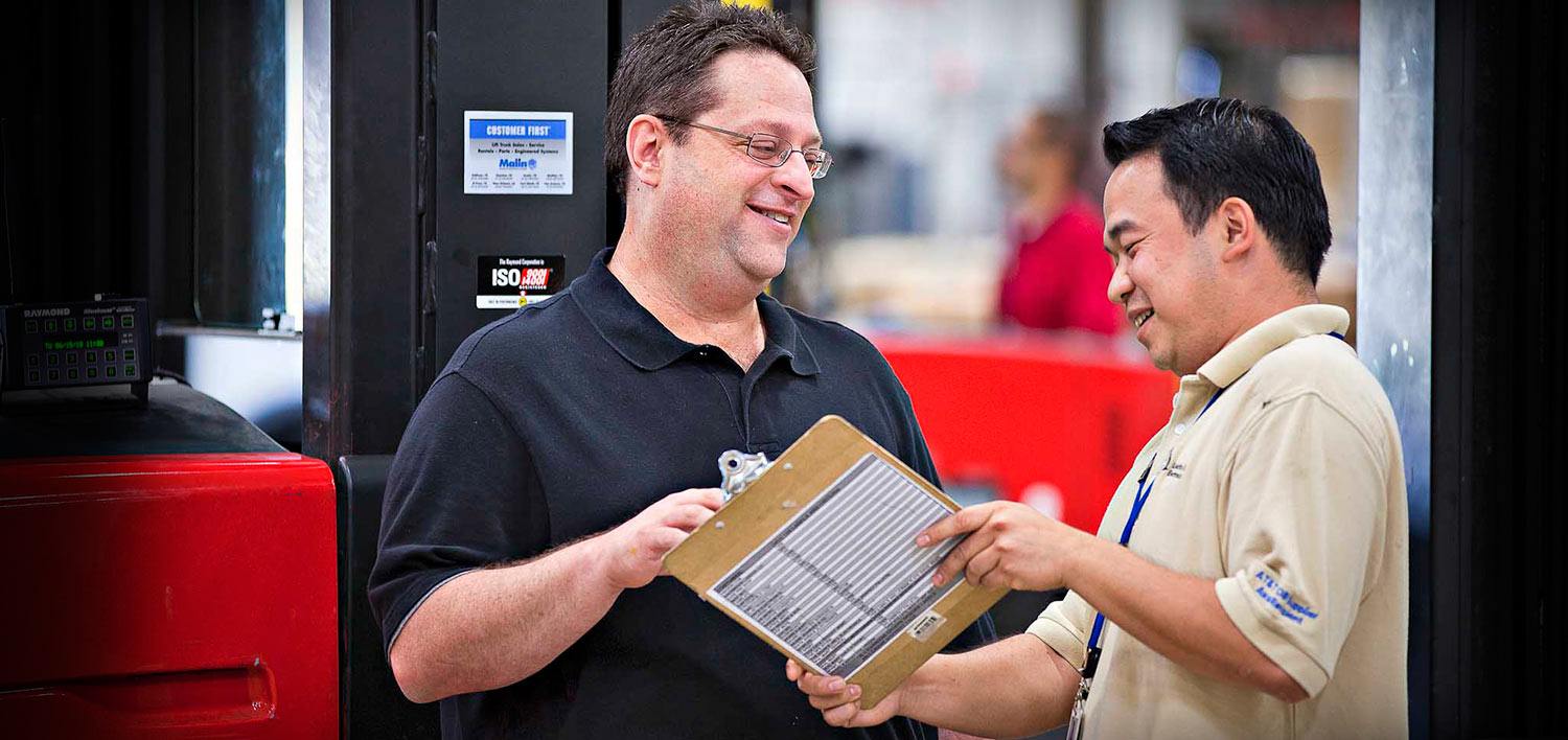 Two men smiling over a forklift agreement